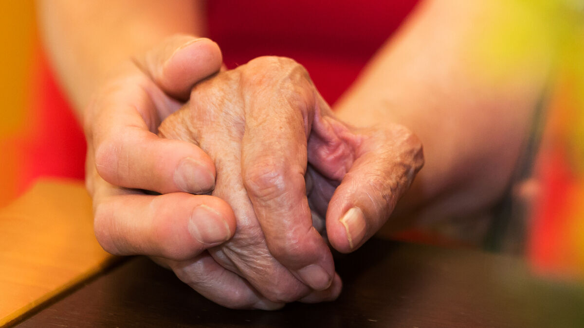 die Hand einer jüngeren Frau hält die Hand einer alten Frau